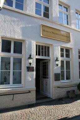 Das Museum Heinrich Friederichs Der Eingang des Heinrich-Friederichs-Museums mit goldenfarbenem Eingangsschild