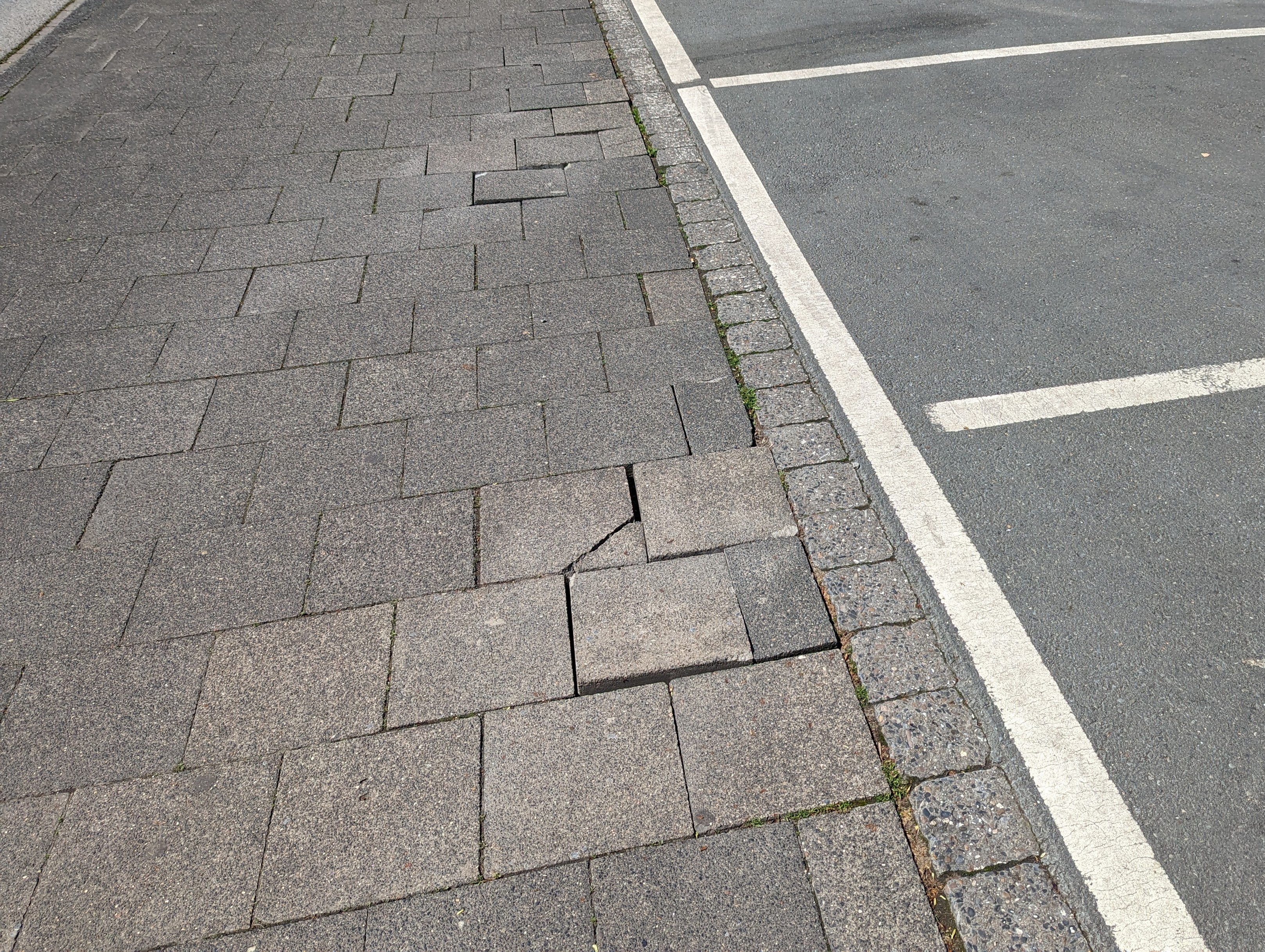 Gehwegschäden Beschädigte Gehwegplatten mit fehlender Bettung.