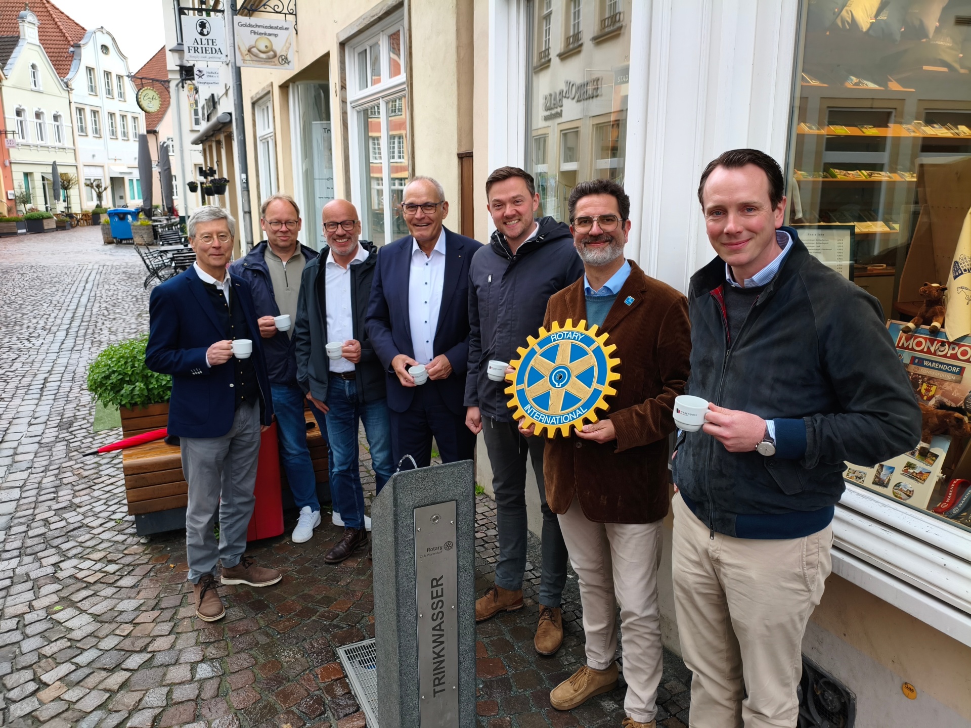 v.l. Egbert Briese (Rotary), Andreas Steiling (Tiefbauamt Stadt), Ulrich Butterschlot (Stadtwerke Warendorf), Peter Scholz (Rotary), Bürgermeister Peter Horstmann, Dirk Assenmacher (Vorsitzender Rotary), Carl Altefrohne (Rotary) nehmen einen Schluck Wasser aus dem Trinkwasserspender an der Tourist-Information an der Emsstraße