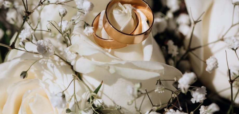 Golden wedding rings on the white rose from the wedding bouquet Golden wedding rings on the white rose from the wedding bouquet